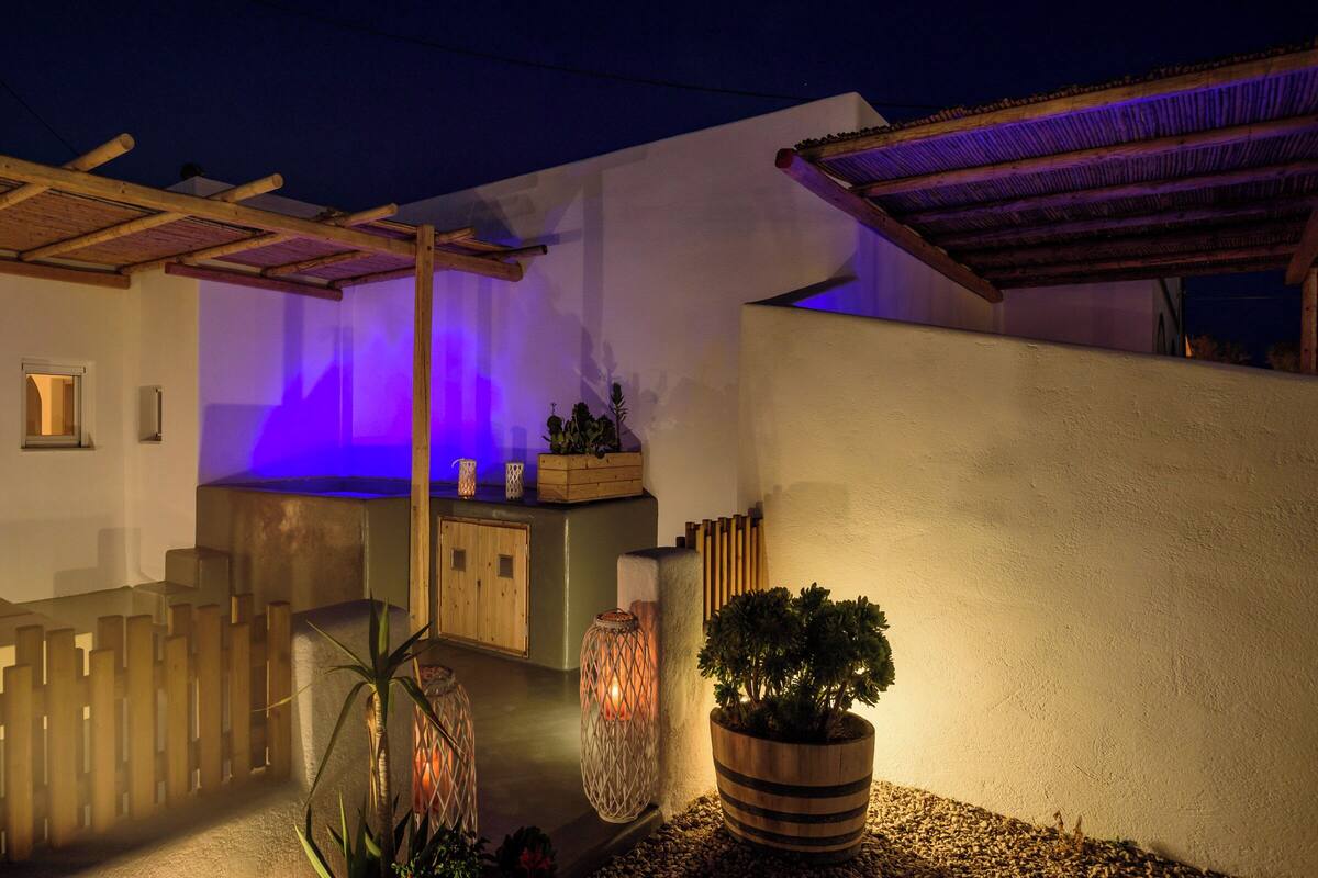 A well-lit outdoor area with a wooden fence, potted plants, and a pergola structure.