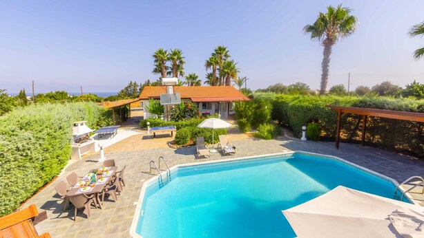 Une piscine avec des chaises longues, une table et des chaises, et un espace barbecue.