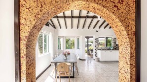 Une cuisine ouverte sur la salle à manger, avec une grande table, des chaises et une arche.
