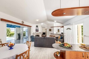 Relax in this stylish living area with a sofa, dining table, and kitchenette, offering a view of the outdoors.