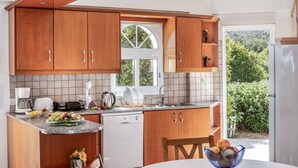 Una cocina moderna con armarios de madera, lavavajillas y ventana con vistas a un jardín.