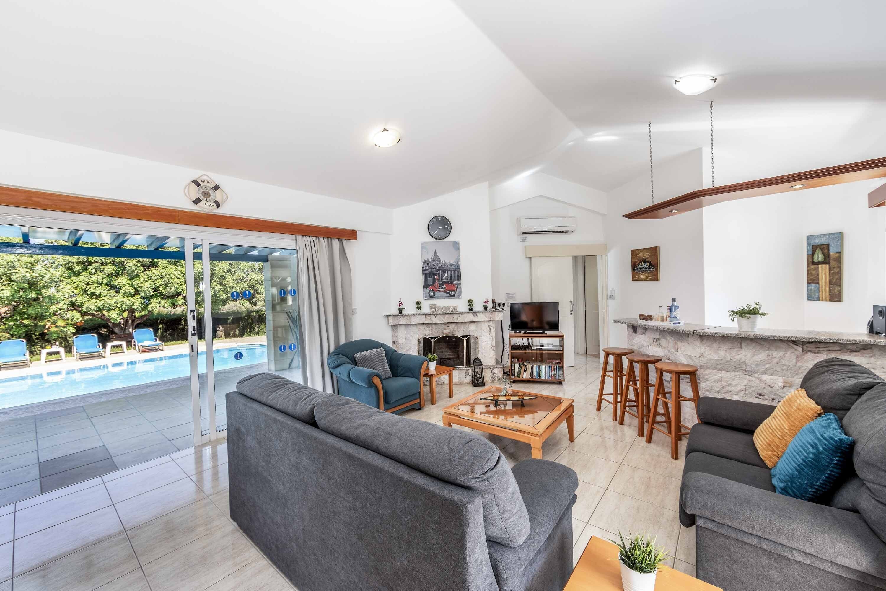 Een moderne woonkamer met zwembad, open haard en een bar.