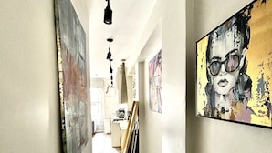 A hallway with artwork on the walls, a wooden floor, and a ceiling with hanging lights. - soho london suite (London)