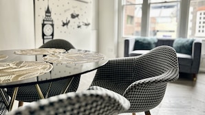 A dining area with a round table, black and white patterned chairs, and a wall with a clock and cityscape artwork. - soho london suite (London)