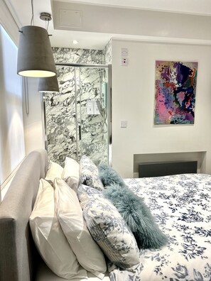 A modern bedroom with a bed, a shower, and a marble wall. - soho london suite (London)