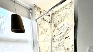 A bedroom with a bed, a window, and a sliding door with a marble pattern. - soho london suite (London)