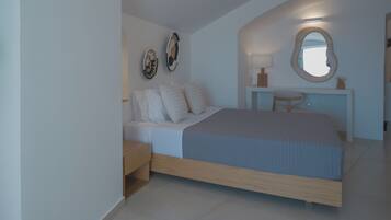 Un dormitorio con cama, mesitas de noche, tocador con espejo y decoración en la pared.