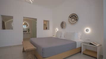 Un dormitorio moderno con una cama grande, mesitas de noche, un banco e iluminación en la pared.