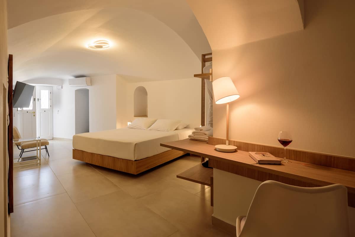 A modern hotel room with a bed, desk, chair, and a glass table.