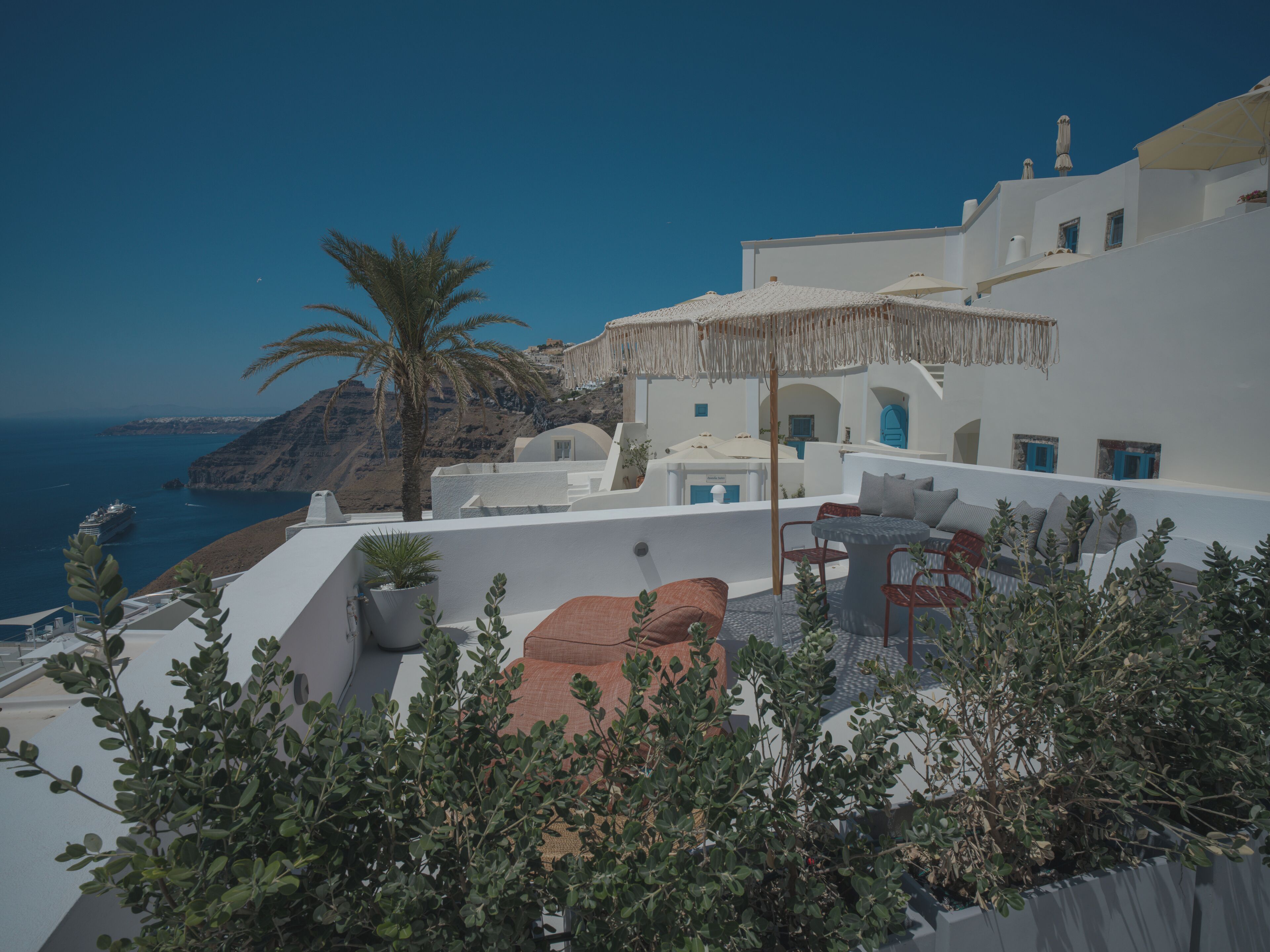 A white building with a terrace overlooking a coastal landscape.
