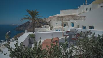 A white building with a terrace overlooking a coastal landscape.