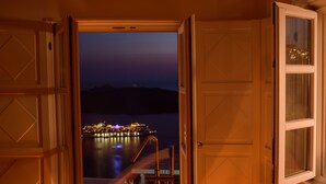 An open door leading to a balcony with a view of a lit-up ship at night. - Anemos Family Suites (Santorini)
