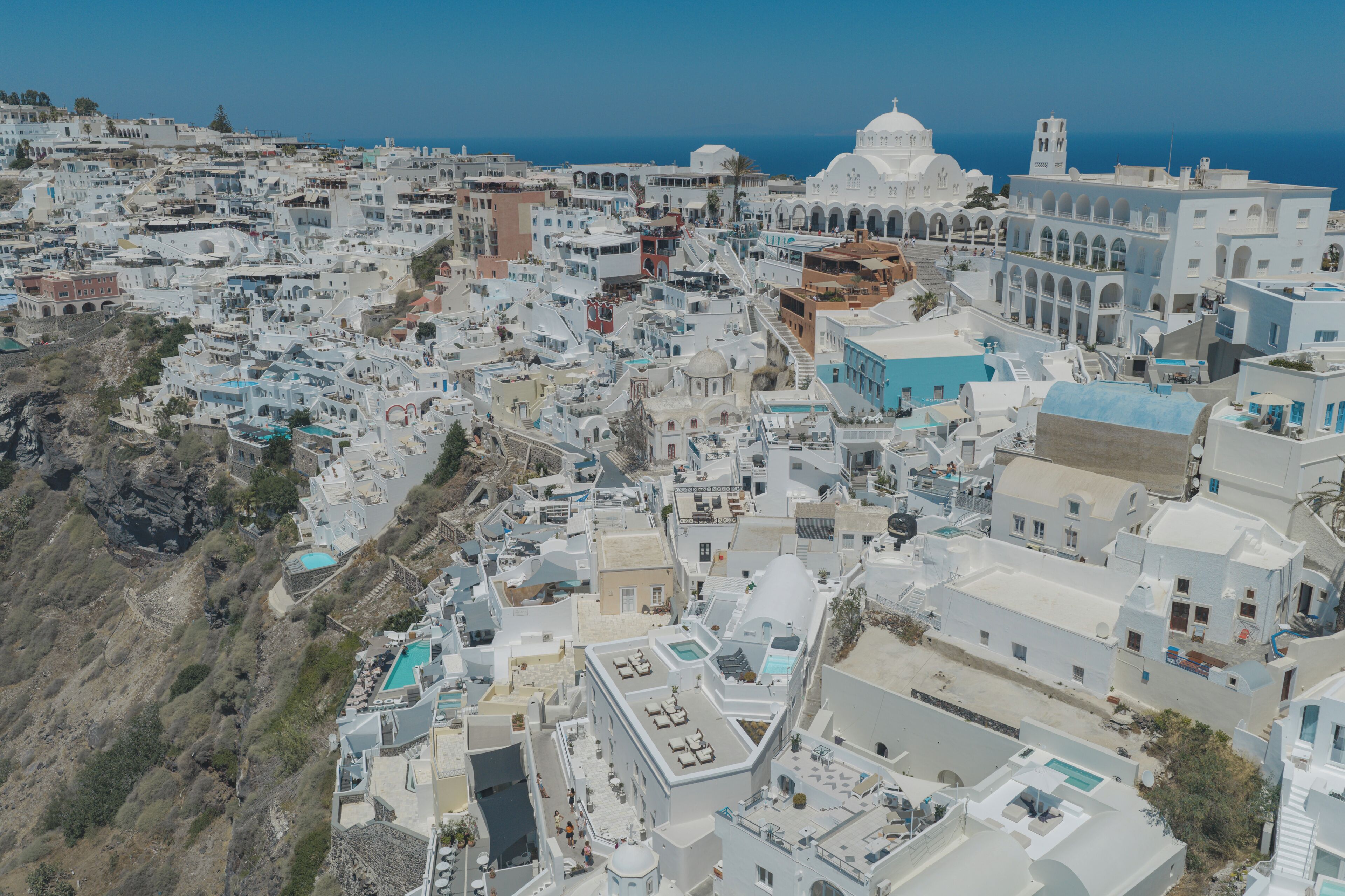 A coastal town with white buildings, a prominent church with a dome, and a clear view of the sea.