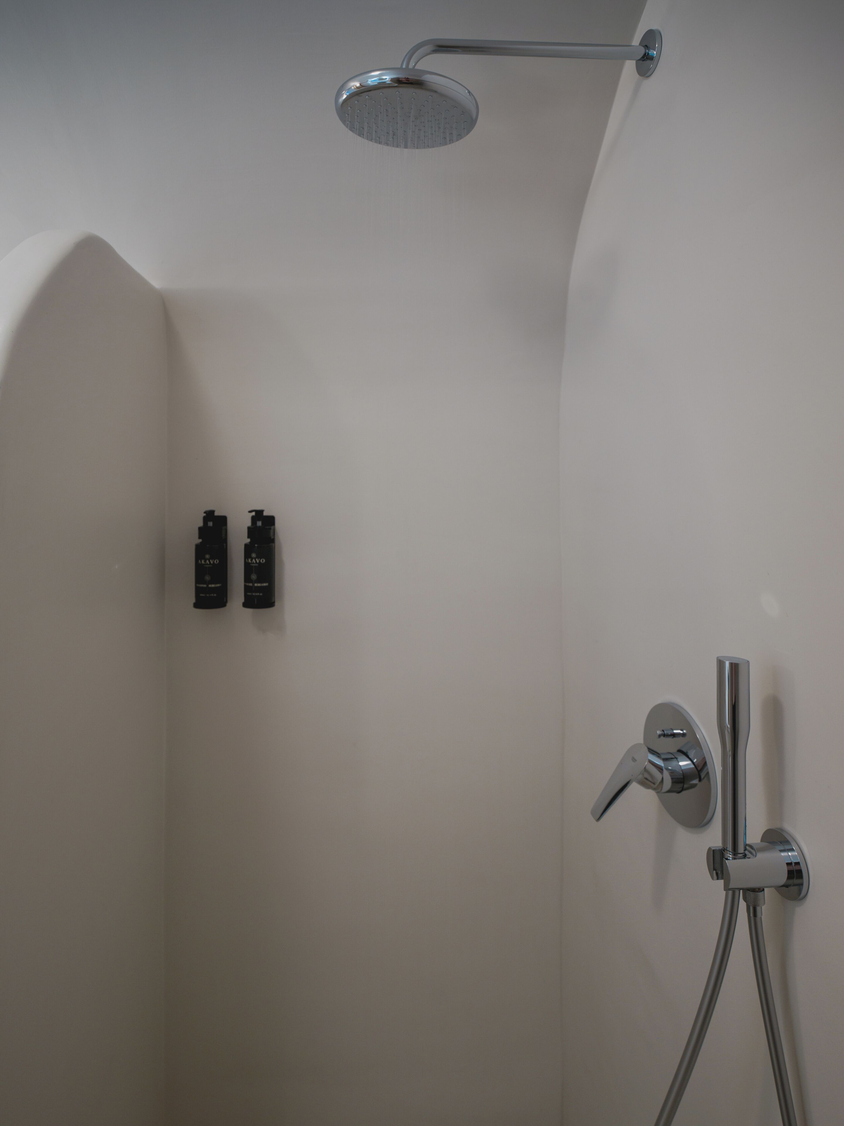 A shower with a handheld showerhead and a wall-mounted faucet.