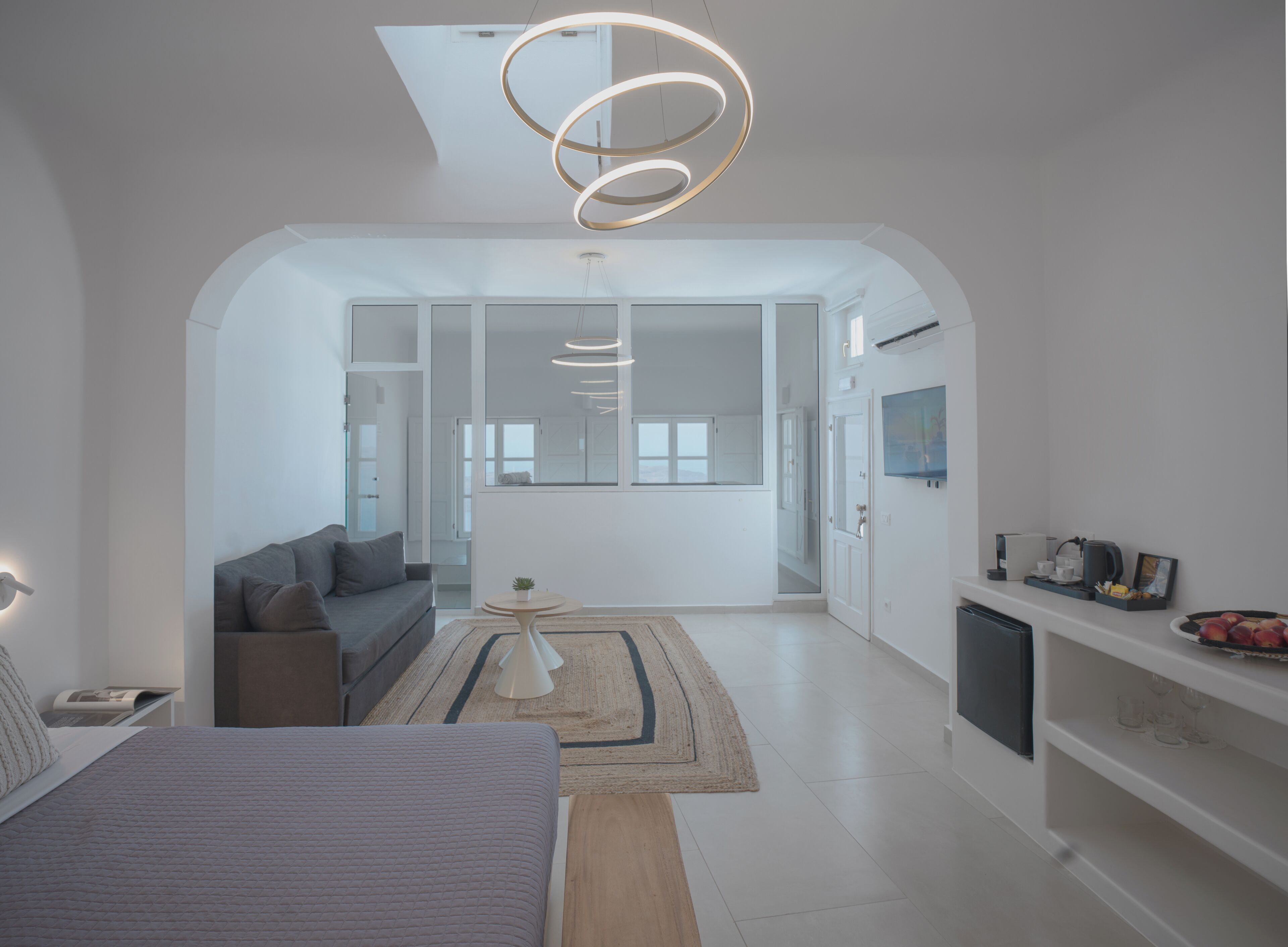 Un intérieur moderne comprenant un lit, un canapé et un coin repas avec un téléviseur et des appareils de cuisine.