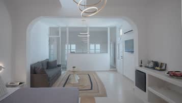 Un intérieur moderne comprenant un lit, un canapé et un coin repas avec un téléviseur et des appareils de cuisine.