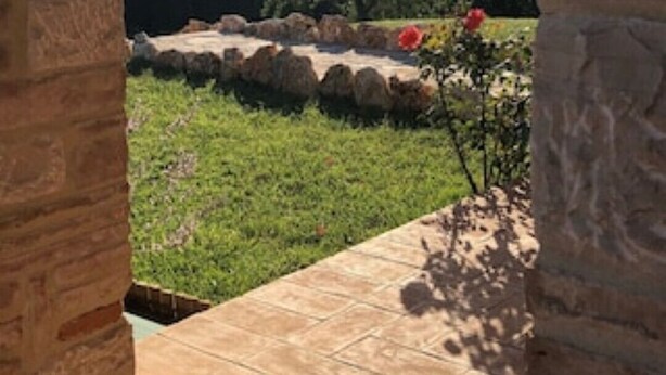 A view through a brick archway overlooking a garden with a stone pathway and a red flower. - Luxury villa in Vasciano (Todi - Umbria) with private pool and fantastic views (Vasciano)