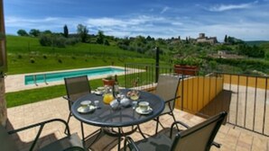 A patio with a round table and chairs, a swimming pool in the background, and a view of a green landscape. - Luxury villa in Vasciano (Todi - Umbria) with private pool and fantastic views (Vasciano)
