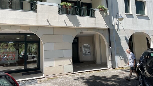A building with a ground-floor entrance, a balcony with potted plants, and a signboard. - Diana apartment, near the historic center bright and spacious (Oderzo)