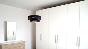 A bedroom with a large wardrobe, a bedside table, and a hanging light fixture. - Diana apartment, near the historic center bright and spacious (Oderzo)