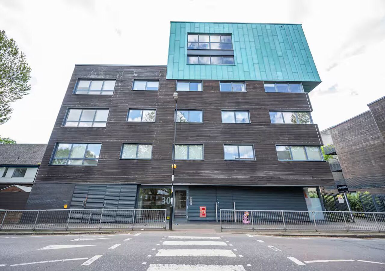 A modern multi-story building with a dark facade and a teal roof.