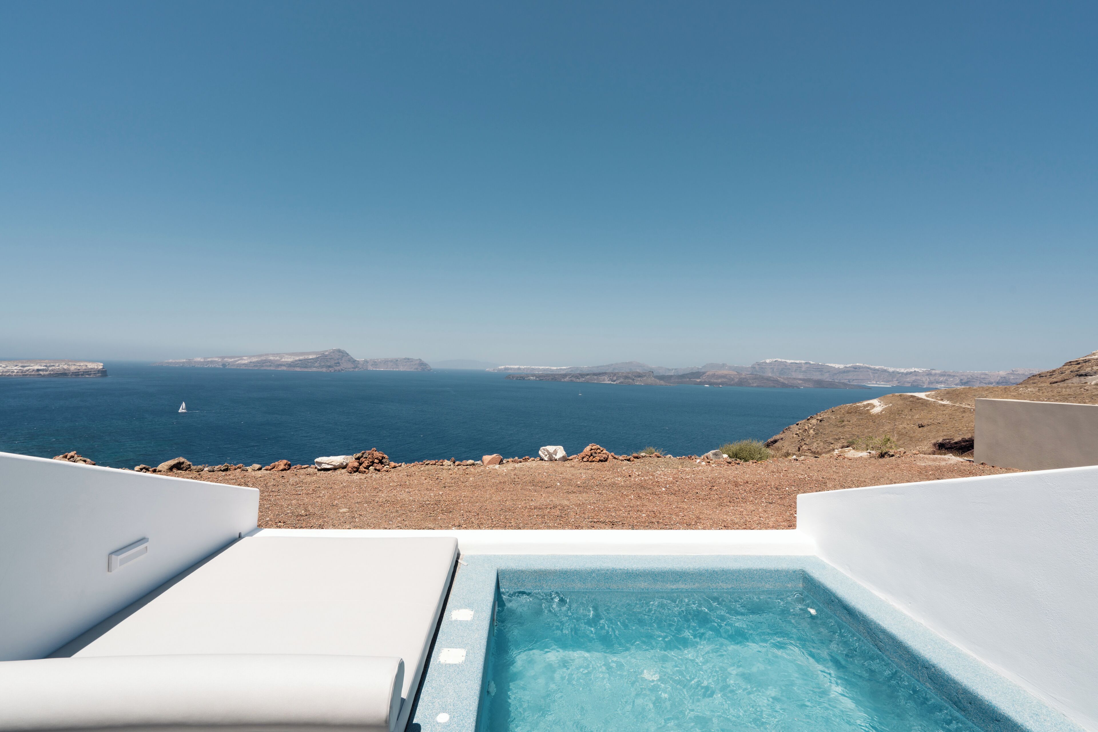 A pool area with a clear view of the sea and distant mountains.