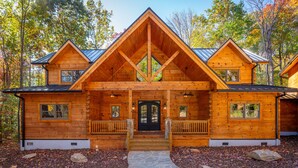 A log cabin with a symmetrical facade, a central entrance with steps, and a stone pathway leading to the door. - Lake Lure's Newest Luxury Log Cabin Behind The Gates of Rumbling Bald Resort! (Lake Lure)