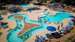 A pool area with multiple swimming pools, lounge chairs, and umbrellas. - Lake Lure's Newest Luxury Log Cabin Behind The Gates of Rumbling Bald Resort! (Lake Lure)