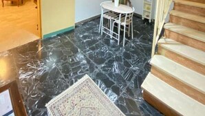 Una habitación con una escalera, una silla blanca y una pared con una frase decorativa.