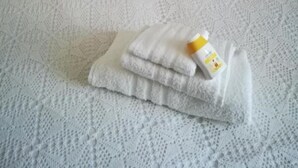 Una cama bien hecha con una colcha blanca texturizada y dos almohadas.