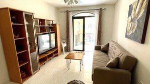 A living room with a TV, sofa, coffee table, and a ceiling fan. - Spacious 3 bedroom apartment within walking distance from Bugibba seafront  (St. Paul's Bay)