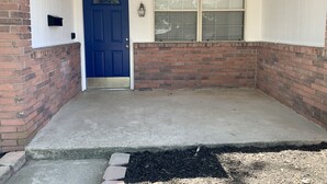 A front porch with a blue door, a window with blinds, and a brick wall. - The House with the Blue Door (Norman)