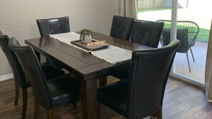 A dining area with a dark wooden table, six black chairs, and a ceiling fan. - The House with the Blue Door (Norman)
