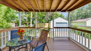 Eine überdachte Veranda mit Tisch und Stühlen, ein kleiner Garten und ein weißer Schuppen im Hintergrund.