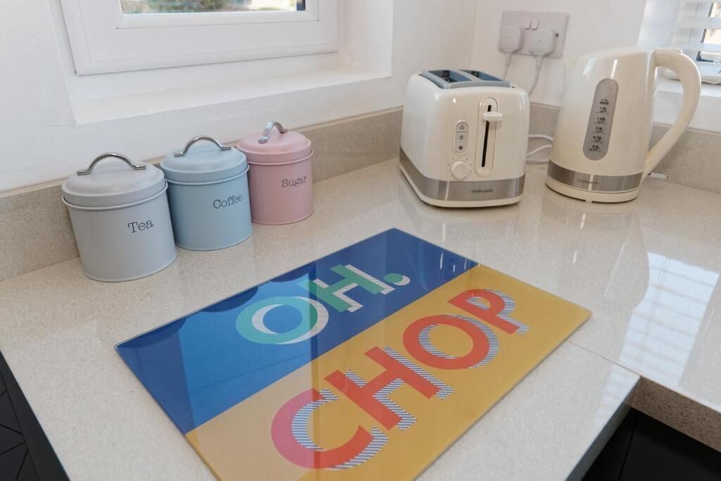 A kitchen counter with a toaster, a kettle, and labeled containers for tea and sugar.