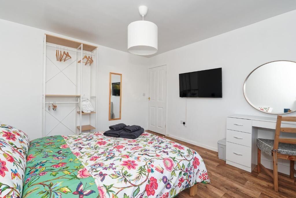 Ein Schlafzimmer mit einem Bett, einem Schreibtisch, einem Stuhl, einem Fernseher und einem Kleiderschrank.