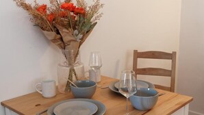 A dining table set with plates, bowls, a wine glass, and a vase with flowers.
