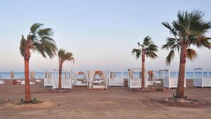 Una playa con palmeras y cabañas de playa.