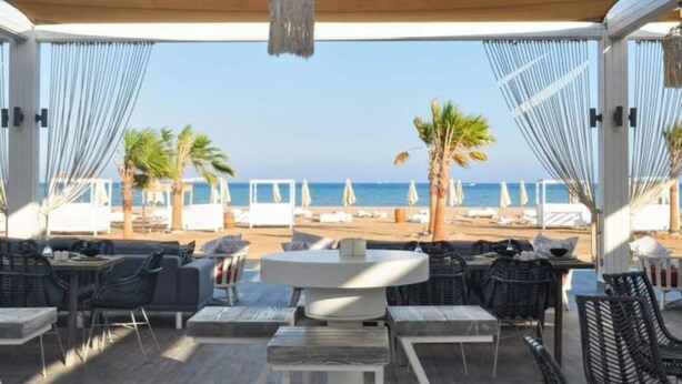 Un espacio de estar techado al aire libre con vista a la playa y al océano.