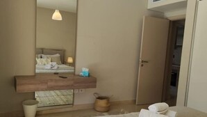 Un dormitorio moderno con una cama grande, una mesita de noche de madera, un espejo y una lámpara colgante.