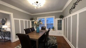 A dining room with a wooden table, chairs, and a vase of flowers. There is a window with blinds, a door with glass panels, and a wall-mounted light fixture. - Spacious 2 bed room apartment near Shaker, Cleveland clinic, CWRU, Van aken.  (Cleveland Heights)