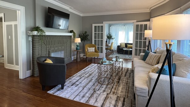 A living room with a fireplace, a sofa, a coffee table, and a TV mounted on the wall. - Spacious 2 bed room apartment near Shaker, Cleveland clinic, CWRU, Van aken.  (Cleveland Heights)
