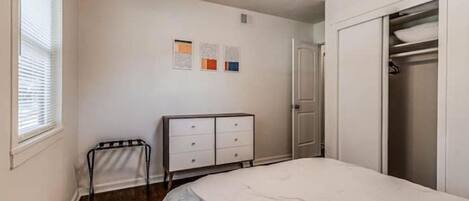 A bedroom with a bed, a dresser, a closet, and a ceiling fan.