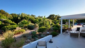 Eine Terrasse mit Sitzgelegenheiten und Blick auf einen angelegten Garten.