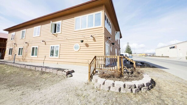 A two-story building with a flat roof and a front porch.
