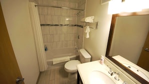Un baño pequeño con ducha, inodoro y lavamanos.