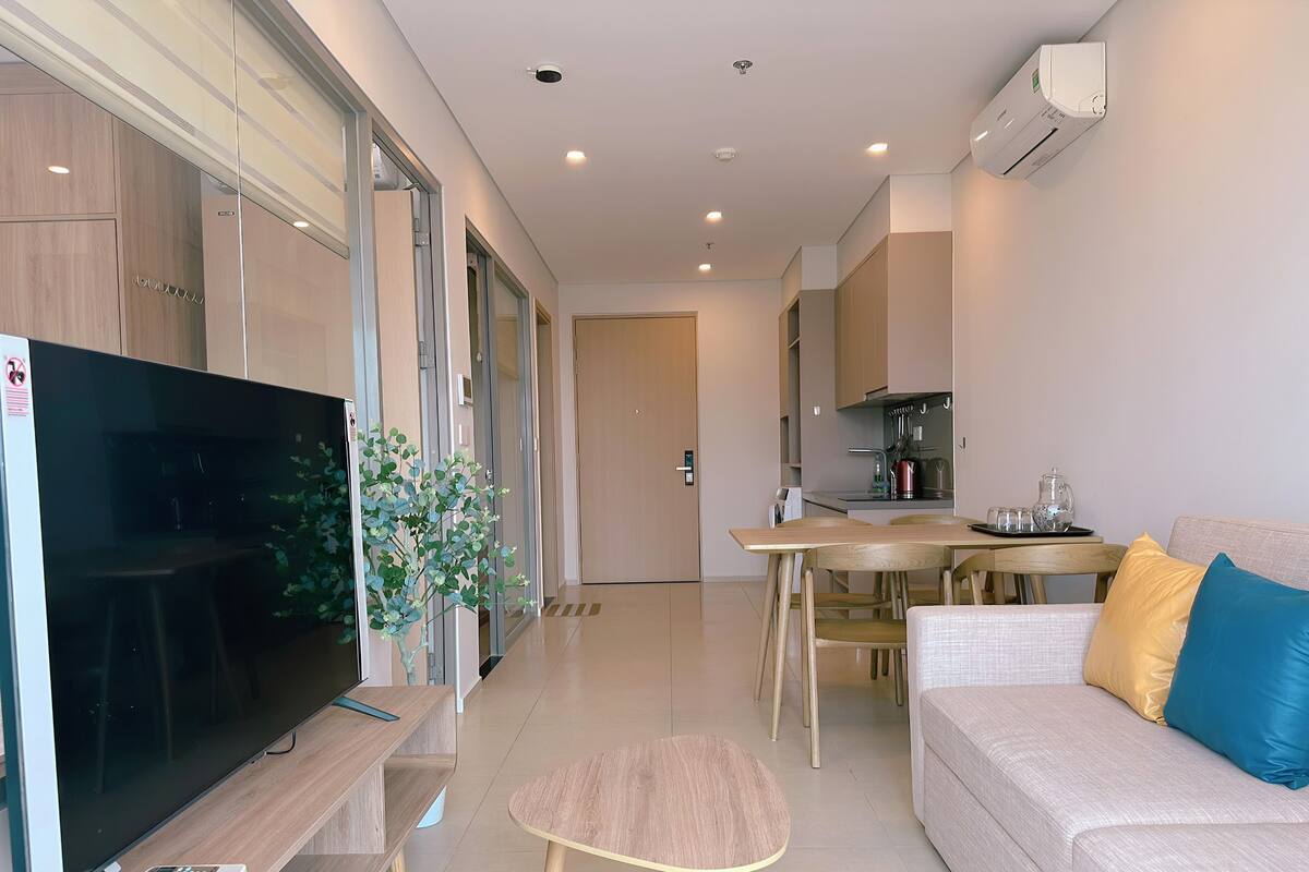 A modern living room with a flat-screen TV, a coffee table, and a sofa with cushions.