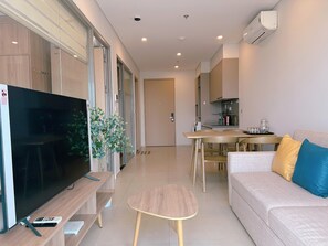 Ein modernes Wohnzimmer mit Flachbildfernseher, Couchtisch und einer Couch mit Kissen.