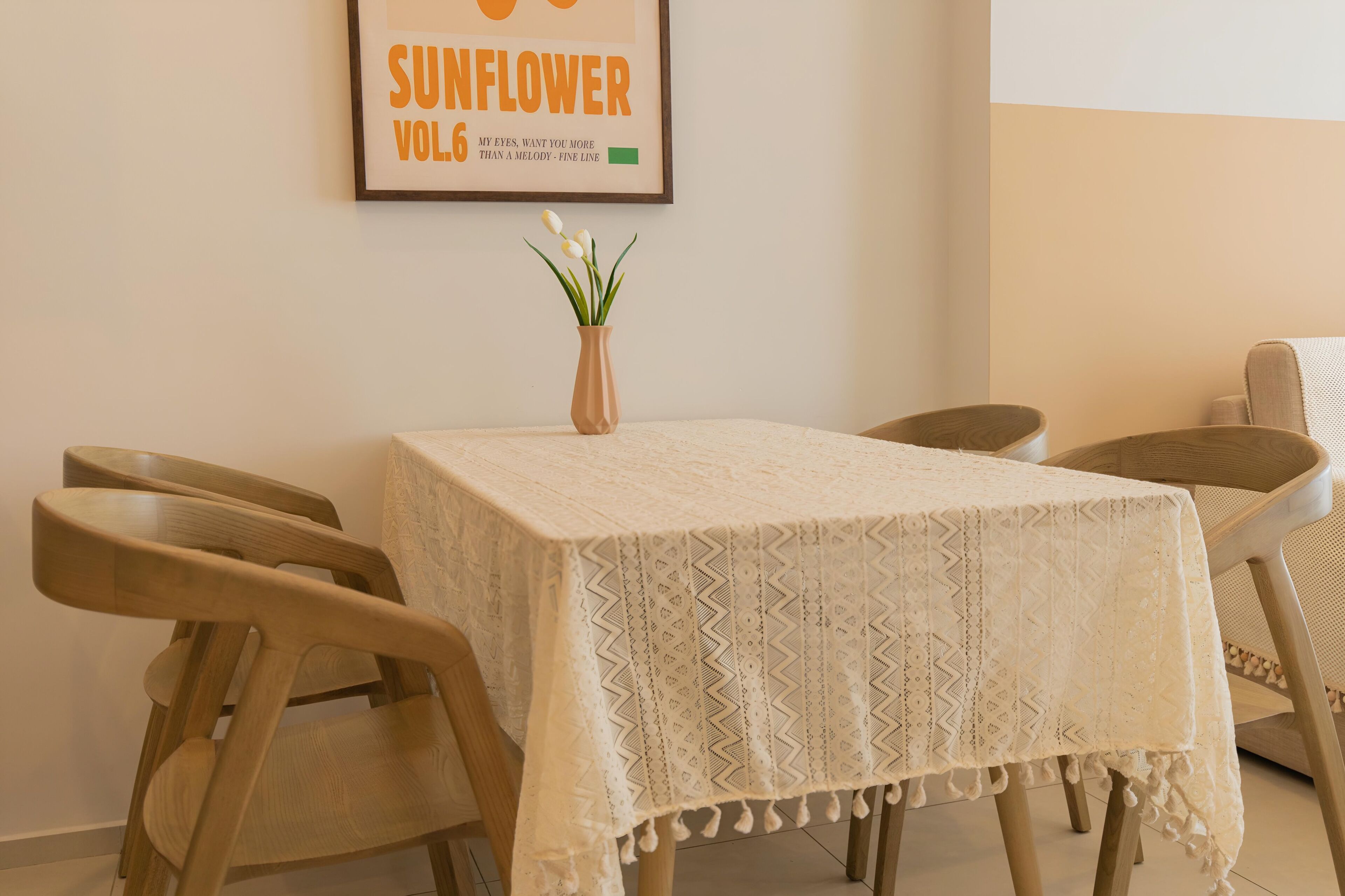 A dining area with a table covered by a patterned tablecloth, surrounded by wooden chairs.