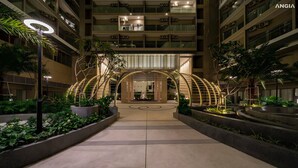 A modern hotel entrance with a central archway, surrounded by greenery and a well-lit pathway. - The Song Vung Tau Apartment Cookies (Ho Chi Minh City)